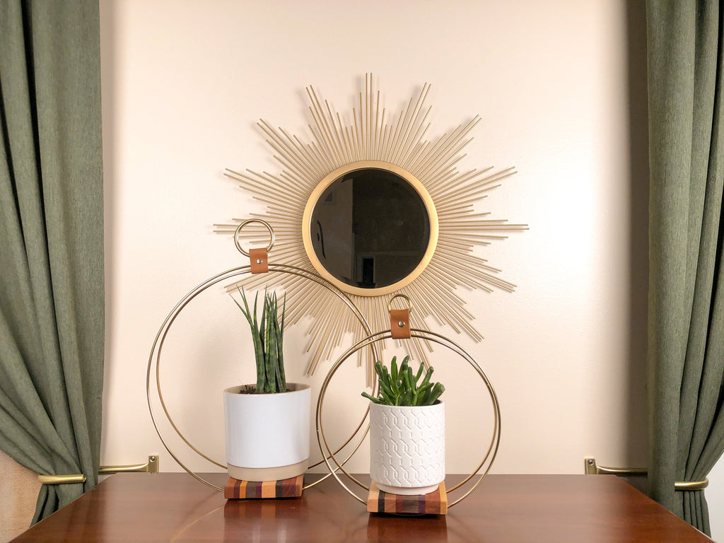 Plant stand on wood surface with starburst mirror